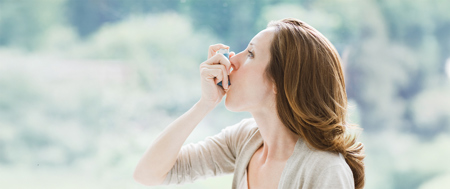 Woman using inhaler device for asthma