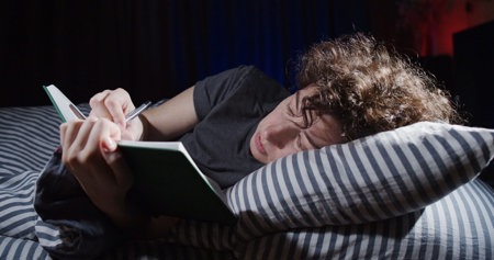 Woman journaling her worries about imposter syndrome and chronic illness in bed
