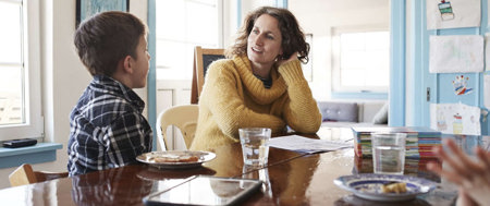 A woman and two children sit at a table, reflecting on family life with a chronically ill parent.