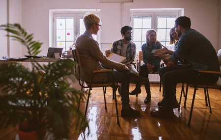 A group of young adults sitting in a room and sharing their mental health stories and experiences.