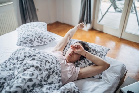 Woman lying in bed, unable to fall asleep because of involuntary movements 