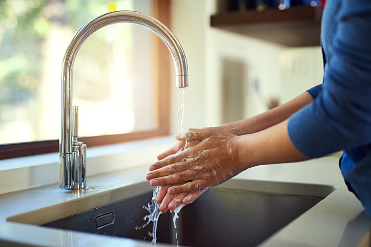 Woman washing her hands to avoid cold and ‘flu germs at kitchen sink