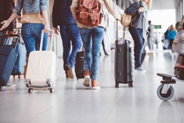Woman wheeling luggage along in the airport, determined to not let her migraine symptoms ruin her and her friends' trip