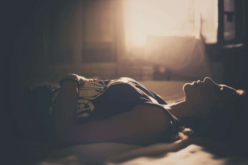 Woman with migraine laying in a darkened room