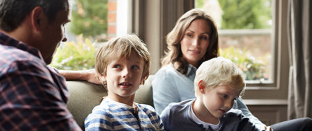 Mother and father sitting with their two young sons in a family meeting about Mom’s chronic illness.