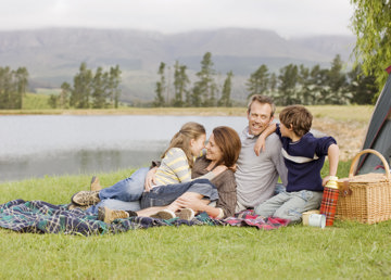 Happy family having picnic by the river, enjoying the weekend, despite migraine