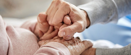 A caregiver gently holds the hand of an elderly individual, symbolizing compassion and shared wisdom in caregiving.