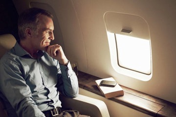 Man with heart failure smiling as he travels comfortably on plane.