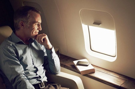 Man with heart failure smiling as he travels comfortably on plane.