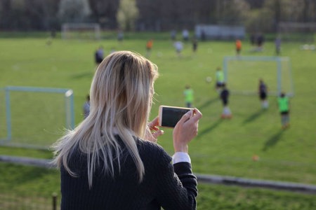 Mom with chronic migraine watching her children playing soccer after school.