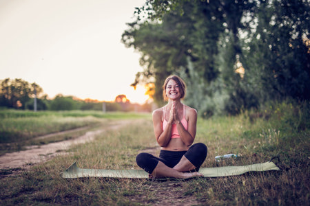 Woman smiling as she practices yoga in a field to help with chronic migraine