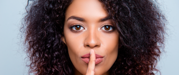 A woman with her finger on her lips, shushing those who negatively stereotype people with ADHD