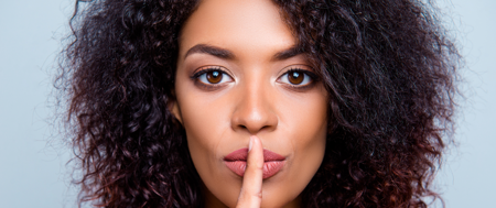 A woman with her finger on her lips, shushing those who negatively stereotype people with ADHD
